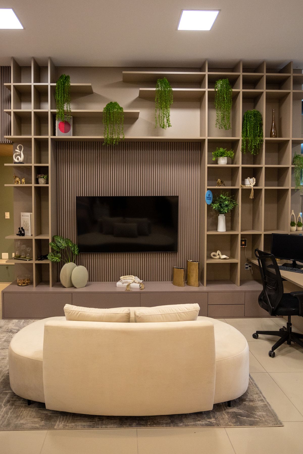 Sala de estar planejada com painel para TV, estante e sofá redondo